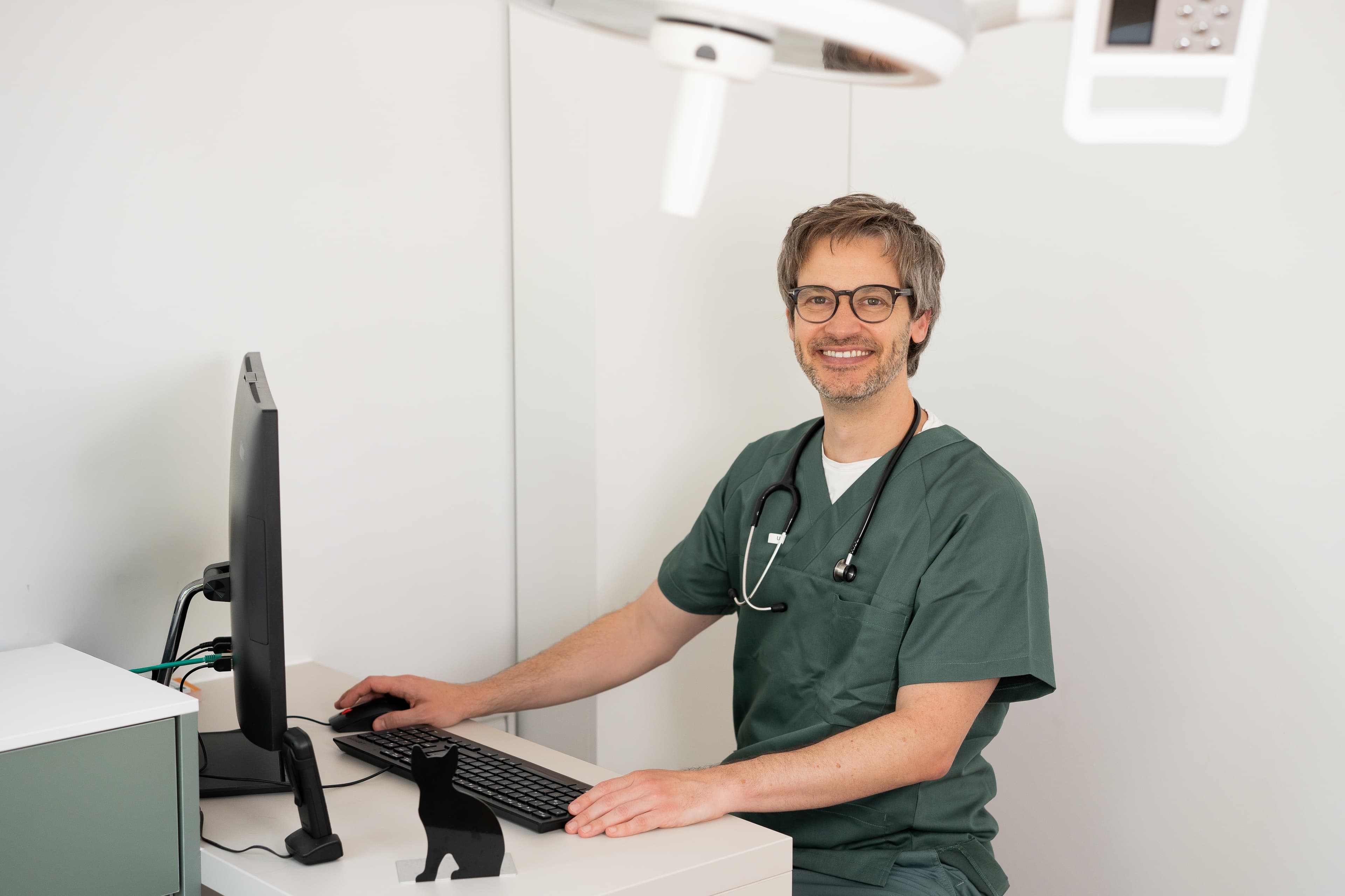 Tierarzt sitzt am Computer im Behandlungsraum